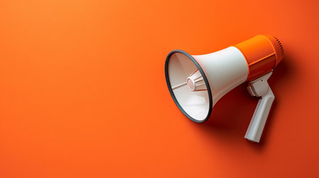 The megaphone stands out against the orange wall, illustrating its purpose for amplifying voices in various settings.の素材