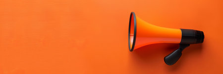 A bright orange megaphone rests against a vivid orange backdrop, emphasizing its role in amplifying voices during events or rallies.の素材