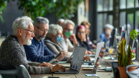 A group of senior learners works diligently on laptops, acquiring essential computer skills in a collaborative and supportive environment.の素材