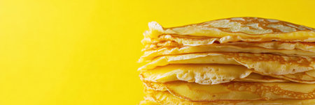 Freshly made golden crepes are stacked high against a vibrant yellow backdrop, ideal for a tempting breakfast or dessert option.の素材