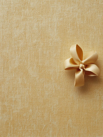 A soft, textured background mimicking gift wrapping paper features a delicate bow placed in one corner, ideal for festive occasions.の素材