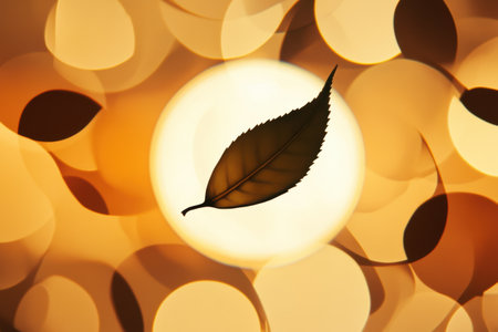 The silhouette of a tea leaf stands out against a warm, luminous backdrop, highlighting its intricate form and natural elegance.の素材
