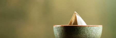 A tea bag is dipped into a green ceramic cup, releasing flavors into the steaming liquid during a calming afternoon ritual.の素材