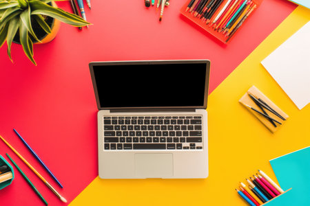 A laptop sits on a colorful desk, surrounded by stationery items, providing a creative workspace for productive activities or study sessions.の素材