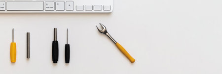 A computer keyboard sits alongside an assortment of screwdrivers and a wrench, ready for hardware repairs in a clean, organized workspace.の素材