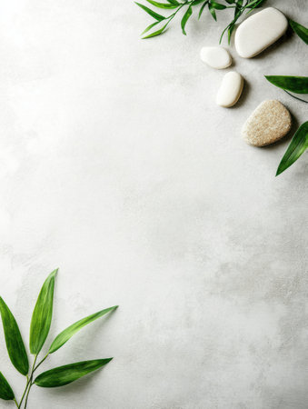 Smooth stones and vibrant green leaves are artistically arranged on a neutral backdrop, creating a serene and minimalist atmosphere.の素材