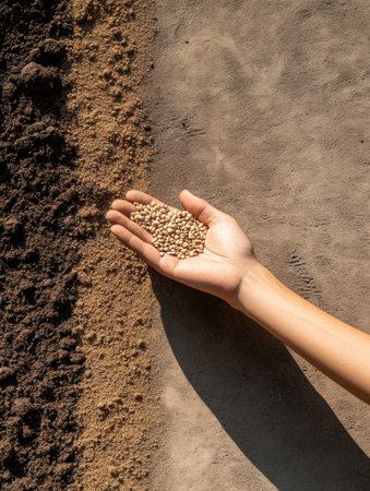 A hand gracefully disperses seeds across rich, dark soil with a gentle motion, symbolizing the start of a new growing season.の素材