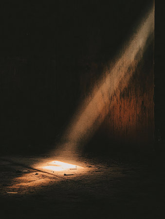A small beam of light illuminates the floor of a dark, deserted space, creating a feeling of abandonment and prompting reflection.の素材