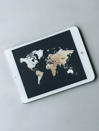 A tablet shows a detailed world map on a neutral background, ideal for design projects with space for additional text or graphics.の素材
