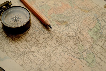 A compass, pencil, and detailed vintage map are arranged with ample copy space for text, inviting exploration and adventure.の素材