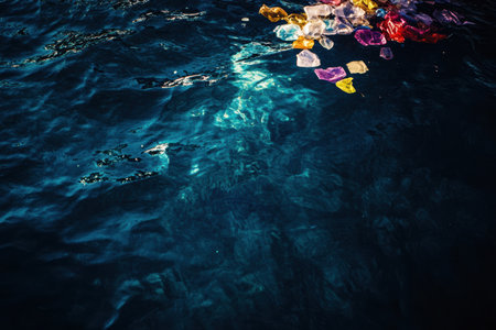 Brightly colored plastic waste floats on the tranquil surface of a deep blue ocean, highlighting pollutions impact on marine environments.の素材
