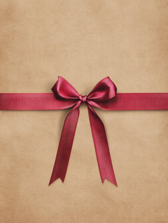A beautifully wrapped gift in textured brown paper featuring a deep red satin ribbon tied in a neat bow, ideal for celebrations.の素材