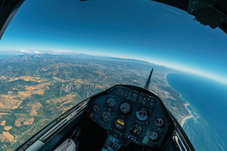 Stunning perspective from a cockpit reveals a panoramic landscape featuring mountains, fields, and coastline under clear blue skies.の素材