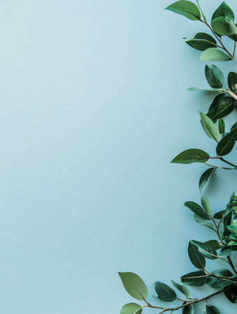 Green leaves are elegantly placed along the edge of a calm light blue surface, showing a simple yet peaceful arrangement.の素材