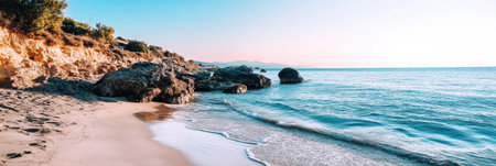 Waves gently lap at the sandy shore while the sun sets behind the distant mountains, creating a peaceful coastal atmosphere.の素材