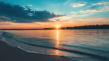 A stunning sunset illuminates the sky with vibrant colors as the sun sets over tranquil waters, creating a serene atmosphere by the shore.の素材