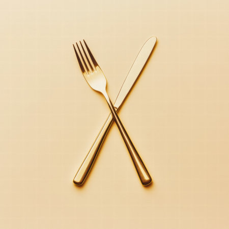 A fork and knife are positioned in a crossed formation, resting on a soft beige background, evoking a sense of culinary elegance and anticipation.の素材