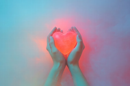 Two hands gently cradle a luminous heart shape, surrounded by colorful lighting and mist, creating a warm and inviting atmosphere.の素材