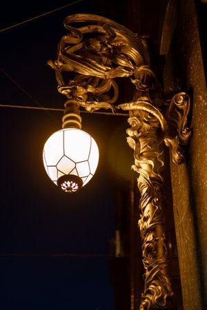 An ornate lamp illuminated against the evening sky highlights intricate artistic details, reflecting the historical architecture of St Petersburg.の写真素材