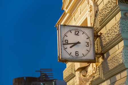 A clock mounted on a beautifully detailed historic building in St. Petersburg shows the time during the evening, highlighting local craftsmanship and charm.の写真素材