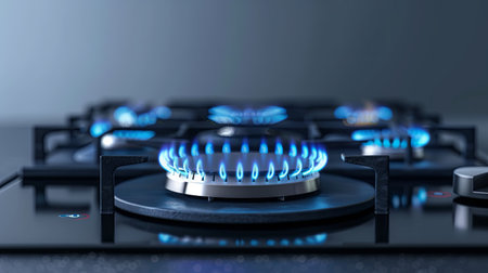 Burning gas stove burner emits vibrant blue flame in a sleek kitchen setting, highlighting concerns about rising gas prices during the economic situation.の素材