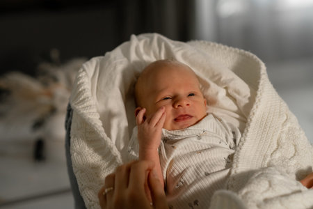 A mother gently interacts with her smiling baby wrapped in a soft blanket inside a warm and inviting...