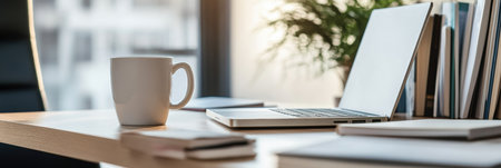 Cozy workspace features a sleek laptop, study books, and a coffee cup bathed in soft natural light, creating an inviting and focused learning atmosphere.の素材