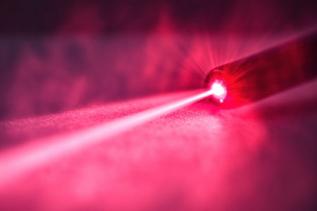 Red laser beam glides over smooth skin in a modern beauty treatment room, illuminated by soft sterile lighting, showcasing advanced skincare technology.の素材