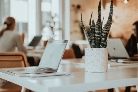 People engage in focused work on laptops in a sleek office space designed for collaboration, highlighted by minimalist decor and soft lighting.の素材