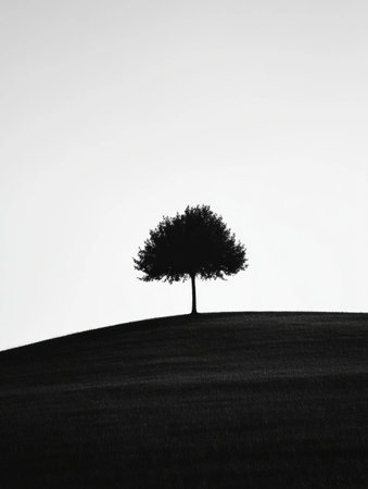 A solitary tree stands proudly on a gentle hill against a backdrop of a clear sky, embodying simplicity and tranquility in a minimalist composition.の素材