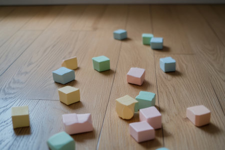 Pastel toy blocks of various colors lie scattered on a natural wood floor, enhancing a minimalist and inviting atmosphere perfect for play and creativity.の素材