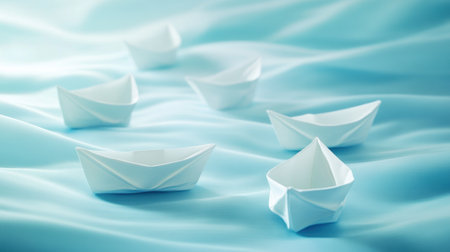Small white paper boats gently drift across a pale blue fabric, creating a tranquil atmosphere that highlights the beauty of simplicity and creativity.の素材