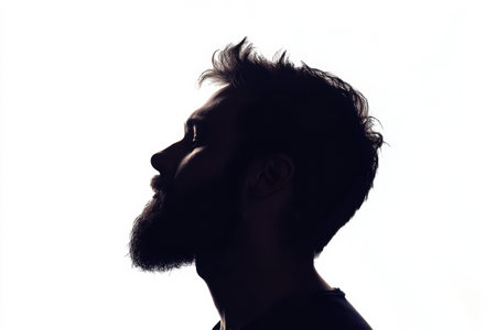 Profile silhouette of a bearded man with a fade effect on a white background, highlighting his facial contours and hairstyle.の素材