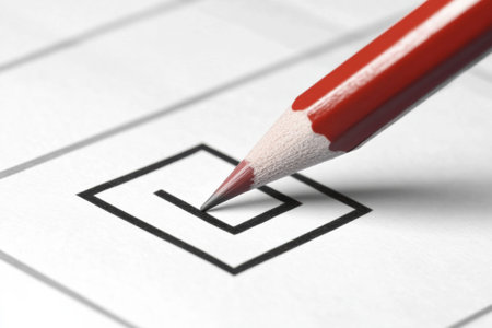 A red pencil is used to mark a checkbox on a ballot paper, demonstrating the act of voting in a clear and minimalistic political context.の素材