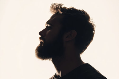 Side profile of a bearded man captured in silhouette with a smooth fade effect on a clean white background offers a striking visual in minimalism.の素材