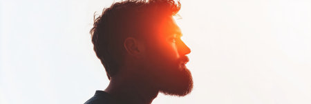 Side profile of a bearded man stands out against a clean white background, evoking feelings of thoughtfulness and calmness highlighted by a subtle fade effect.の素材