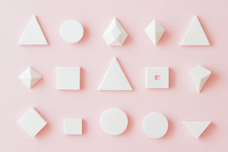 White sticker shapes displaying various geometric forms are neatly positioned on a soft pastel pink background, ideal for artistic or design inspiration.の素材