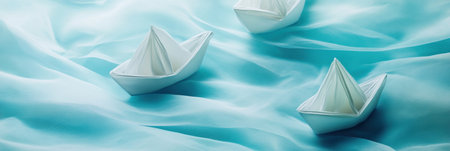 Delicate paper boats gently float across a smooth pale blue fabric, creating a tranquil and poetic atmosphere that inspires creativity and calmness.の素材