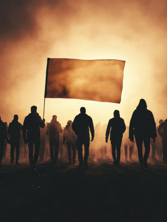 Protesters gather in a foggy atmosphere, silhouetted against a dramatic backdrop, while raising banners to express their views during an evening demonstration.の素材
