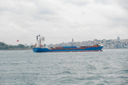 A cargo ship navigates the Bosphorus Strait with Istanbuls skyline under gray skies, highlighting...