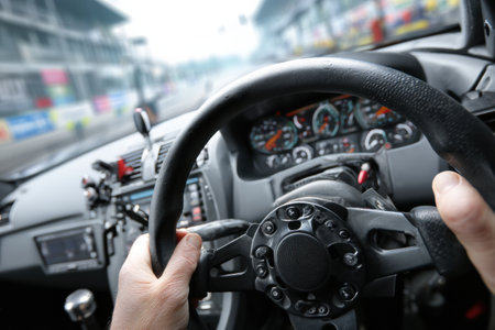 Hands grip the steering wheel tightly, showcasing intense concentration while navigating the quick turns of a racetrack under overcast skies.の素材