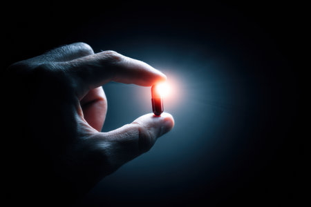 A hand gently cradles a glowing pill against a dark backdrop, representing the concept of healing and the pursuit of better health.の素材
