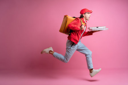 A courier in a bright outfit sprints energetically against a colorful background, carrying a pizza box and pushing to meet a delivery deadline.の素材