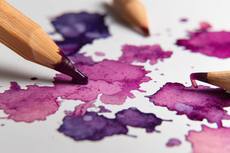 Ink blots in varying shades of purple create a playful and artistic background. Colored pencils are positioned nearby, inviting creativity and sketching.の素材