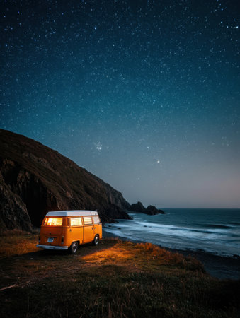A vintage camper van is parked on a cliffs edge, illuminated by warm light, while stars twinkle in the clear night sky above the ocean.の素材