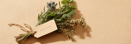 A carefully arranged herb bundle with a label tag sits on a soft beige backdrop, showcasing an inviting display of fresh herbs and earthy tones.の素材