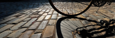 A vintage bicycle rests on a cobblestone street, casting a detailed shadow as the sun sets, highlighting the textures and warmth of the scene.の素材