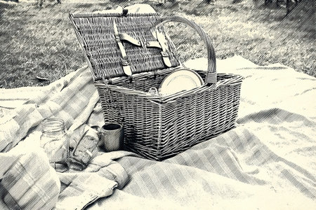 A monochrome sketch depicts an open picnic basket resting on a soft blanket in an outdoor space, suggesting a relaxing meal amidst nature and tranquility.の素材