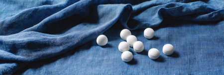 White pills are artfully scattered on a smooth blue fabric, creating a minimalist still life that evokes simplicity and tranquility.の素材