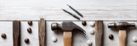 Various hammers and nails are laid out neatly on a textured wood surface, showing their essential role in construction and craftsmanship activities.の素材